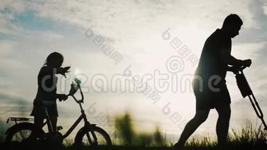 比基尼家庭剪影，父母带着两个孩子骑自行车在日落。 友好家庭观念..
