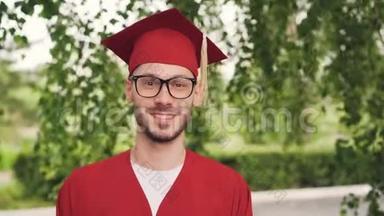 戴着眼镜、<strong>毕业</strong>礼服和灰泥板的留着胡子的青年<strong>毕业</strong>学生的肖像，微笑着看着