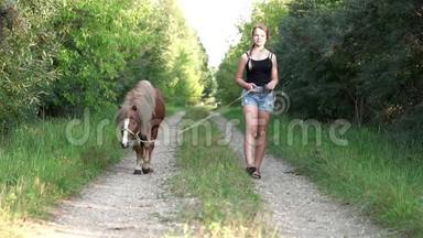 夏天，少女和一匹小马在美丽的<strong>乡间小路</strong>上散步