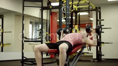 体育运动员在健身房做哑铃凳<strong>式按压</strong>练习