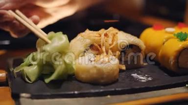 女人手拿筷子蘸着<strong>寿司</strong>卷进<strong>酱油</strong>。 卷和生姜，鲑鱼<strong>寿司</strong>和生姜