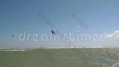 在海滩营地的背景下，一个穿着风筝的人在空中跳得很高