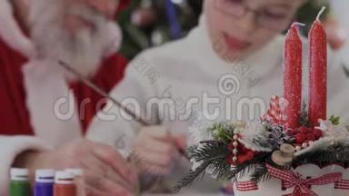 圣诞老人和小男孩在两支节日蜡烛模糊的背景下画画