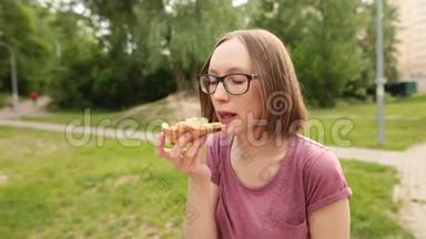 时髦的高加索女人戴着眼镜，坐在长凳上吃着一片美味的披萨。