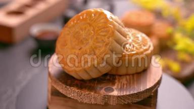 美丽的月饼在木制托盘上旋转，<strong>黑色石板</strong>背景上有茶和花。 中国传统中秋节