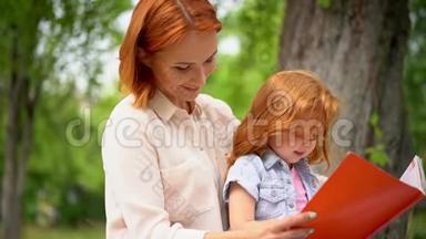 母亲和女孩<strong>坐在树下</strong>看书