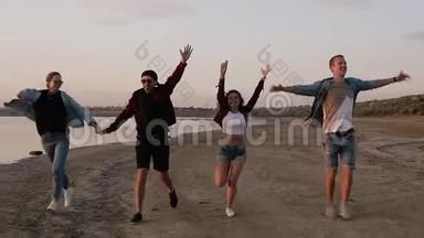 <strong>一</strong>群朋友在海滩上快乐地<strong>一起跑</strong>步。 自由，快乐和幸福.. 举起双手飞向天空