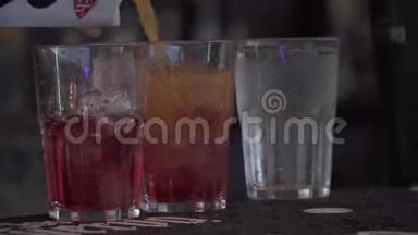 果汁被倒进站在酒吧的玻璃杯里。 酒保准备鸡尾酒特写。