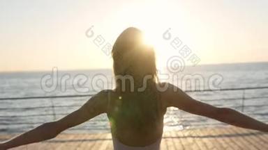 年轻女子举起双手缓慢地走在海边背景下。 窈窕<strong>淑女</strong>，阳光明媚
