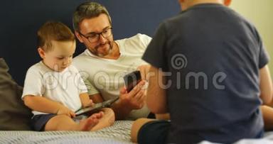 父亲和孩子在床上使用手机和数码平板电脑