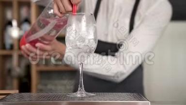 一位年轻英俊的酒保把汽水虹吸管里的一杯汽水倒进了装有冰块的杯子里。