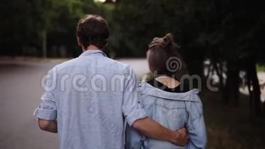 一对年轻夫妇穿着<strong>类似</strong>的蓝色衬衫，在公园散步。 浪漫，平静，约会