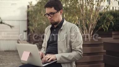 年轻的商人坐在长凳上用笔记本电脑开发一个<strong>创业项目</strong>