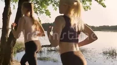 两位年轻漂亮的女跑步者在河边公园慢跑，健身模特跑步，美丽的自然背景