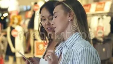 两个年轻漂亮的女购物狂在购物中心上网寻找折扣