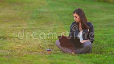 公园里的一个女孩在草坪上用笔记本电脑工作，<strong>电话铃</strong>响，接来电话。
