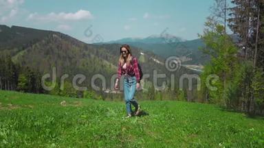 一个年轻的白人女人带着背包和太阳镜站在山上，拿起她的手。 的概念