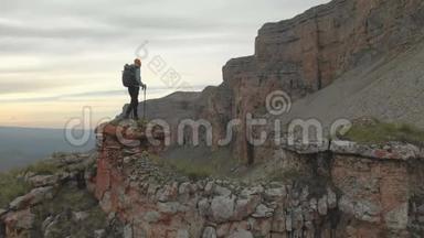 空中飞行经过向前行走的成年女子背着背包坐在史诗脚下的岩石上休息