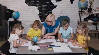 小学漂亮的孩子在教室里画画，老师帮忙。 孩子们和老师一起画画