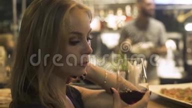 年轻女子手捧红酒杯在咖啡馆里。 在餐厅的活动派对上，女人品尝和喝红酒。