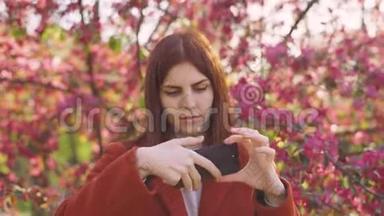 年轻迷人的红发女人在智能手机上拍摄<strong>樱花</strong>或<strong>樱花</strong>春花的<strong>背景</strong>自拍。
