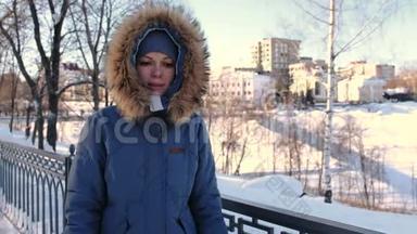 穿着蓝色<strong>羽绒服</strong>的年轻女人，带着毛皮罩在冬天的公园里散步，在街上冻僵了。 前景。