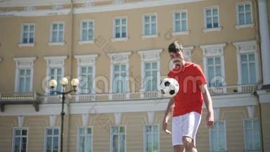 美丽的城市广场上，英俊的男子足球运动员独自用脚和胸部踢球