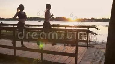 两个年轻的女人在<strong>公园</strong>里穿过大桥，停在<strong>河边</strong>，日落时分，减肥，美丽的景色