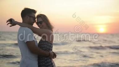 日落时在海边拥抱的迷人情侣的户外。 蜜月度假的概念..