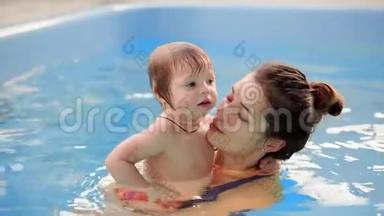 年轻的妈妈在游<strong>泳池里</strong>慢动作地和她的小女儿<strong>玩耍</strong>。 积极生活方式的体育家庭