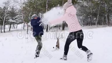 快乐的母子玩雪球，在寒冷的冬日在树林里撒粉。 女人和男孩有雪战