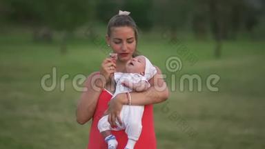 年轻的母亲抱着她的孩子在城市公园玩耍，她站在那里，穿着鲜<strong>红</strong>的<strong>裙子</strong>-儿子穿着