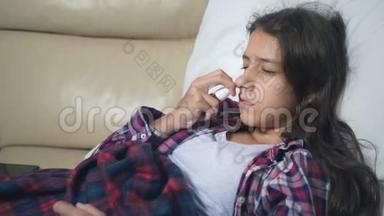 十几岁的女孩感冒了，吹着鼻子躺在被子下面的沙发上。