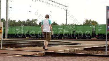 一个戴着耳机的年轻人穿过铁轨，听着音乐，听不到即将到来的火车