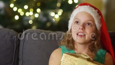 那个女孩许下<strong>圣诞</strong>节的<strong>愿望</strong>。 戴着<strong>圣诞</strong>帽的棕色眼睛女孩的亲密肖像，手里拿着礼品盒。 <strong>圣诞</strong>节