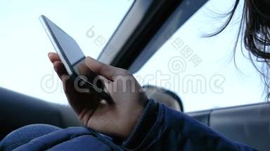 有手机的女人在车里。 特写女`用手机浏览网页。