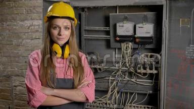 年轻自信的女建筑工人站在电线和<strong>电表</strong>附近交叉双臂，看着摄像机，建筑