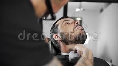理发师在理发店用剪子剪了顾客`胡子，男人在理发`剪了胡子