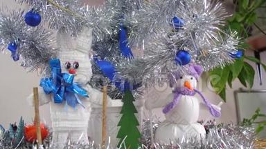 圣诞树下手工制作的圣诞玩具，野兔和雪人。 孩子们房间里的银色圣诞树`装饰