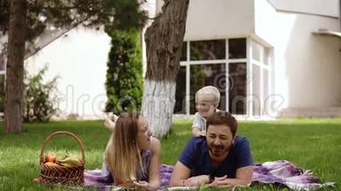 快乐快乐的年轻家庭爸爸、妈妈和小儿子在户外玩得开心，一起在夏天的公园玩