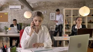 年轻严肃的女商人正在办公室里打电话，看报纸，人们正在与科技建立联系