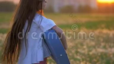 在日落时分，有趣的小女孩在蒲公英地弹吉他。 <strong>远离</strong>城市建筑的户外情感和乐趣