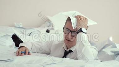 一个戴眼镜的疲惫的年轻人坐在一堆文件和签名文件里。 他把头捏在<strong>手心</strong>里