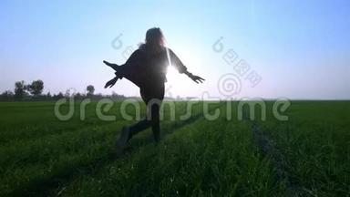 美丽的年轻金发女孩在日落的天空上的绿色麦田上<strong>奔跑</strong>。 <strong>自由</strong>概念。 户外快乐的女人。 收获