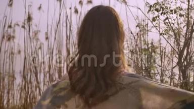 年轻的<strong>姜黄色</strong>微笑的女孩，穿着一件连衣裙，站在大自然的树林里，远远地看着相机50fps
