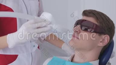 戴着红色防护眼镜的年轻人在牙医那里接受紫外线美白