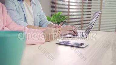 年轻的亚洲家庭夫妇使用笔记本电脑讨论新闻或做网上购物一<strong>起坐</strong>在办公桌上周末在家里。