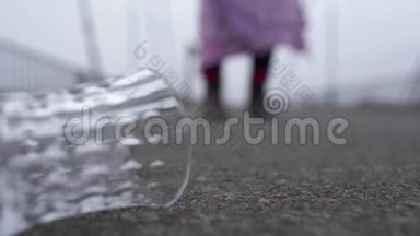 铺在人行道上的玻璃特写。 一位衣衫褴褛的老妇人在模糊的地面上行走