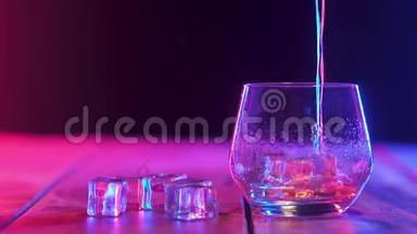 在装有冰块的玻璃<strong>杯中</strong>，<strong>倒入</strong>浓香的威士忌。 彩色照明