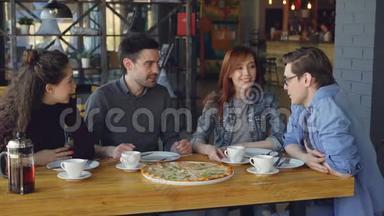 <strong>亲密</strong>的朋友，年轻的男人和女人正在分享大比萨饼，在舒适的咖啡馆里吃美味的食物，聊天。 友谊